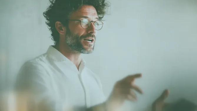 Tutor delivering a lesson, with animated expression and pointing.