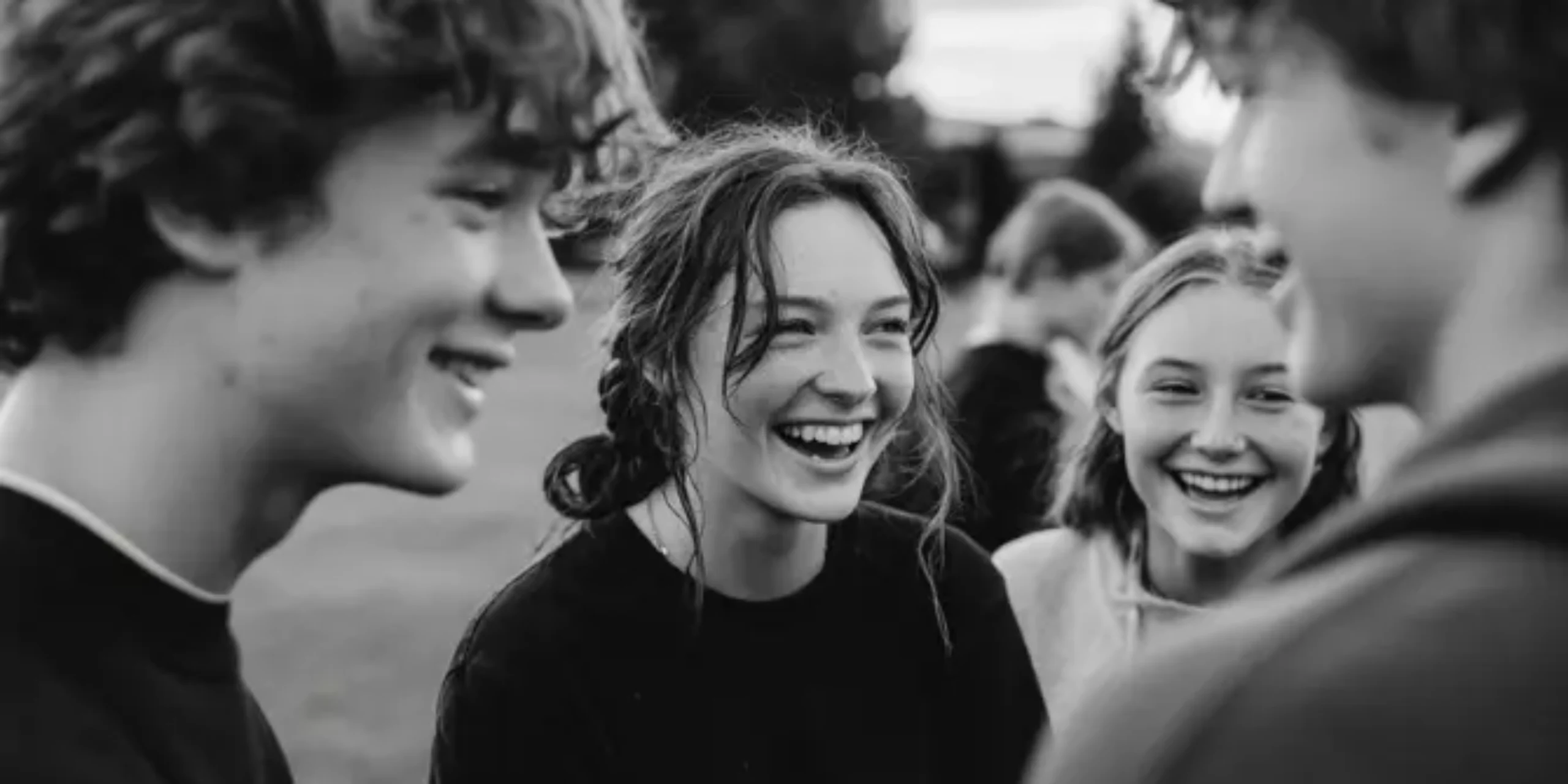 Group of teenagers laughing together in a field during a teen support programme