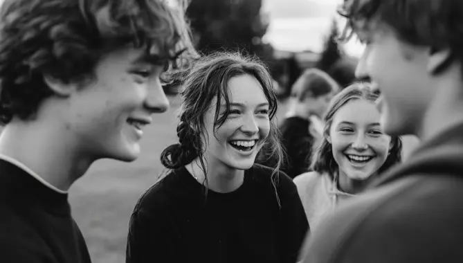 Group of teenagers laughing together in a field during a teen support programme