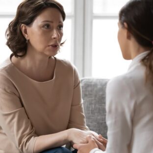 Woman speaking and holding hands with another person during a one-to-one session