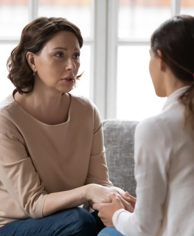 Woman speaking and holding hands with another person during a one-to-one session